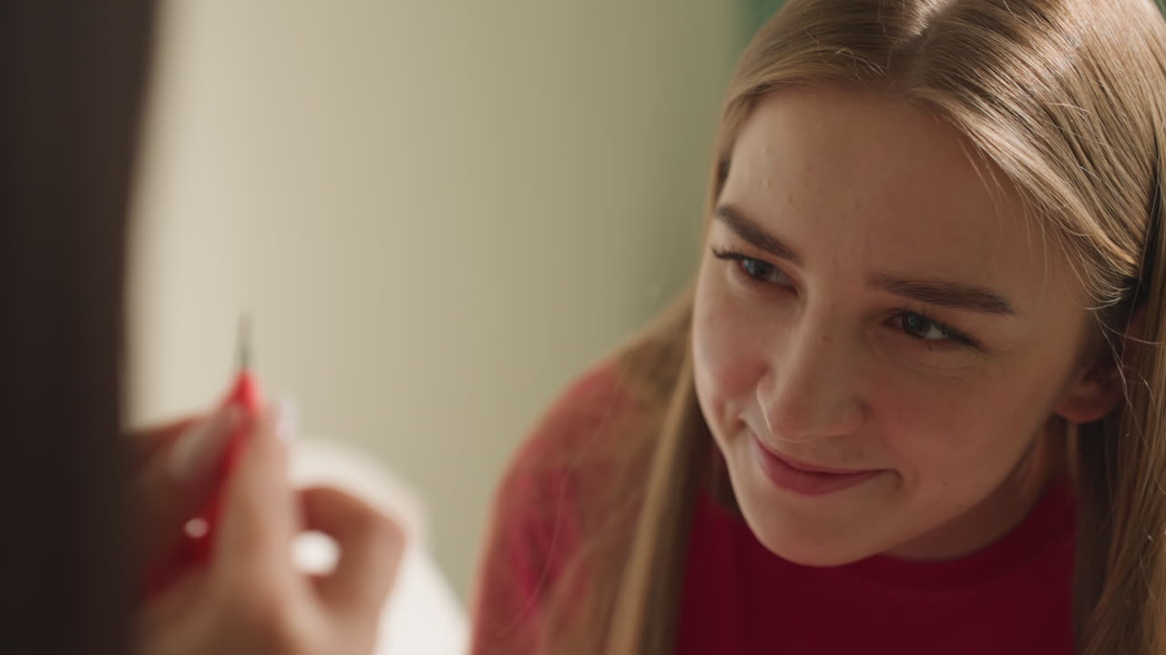 Una chica revisa una joya, una mujer examina atentamente un pequeño adorno, una mujer revisa cuidadosamente una pequeña pieza decorativa con atención, una joven examina minuciosamente una joya frágil bajo una luz suave.