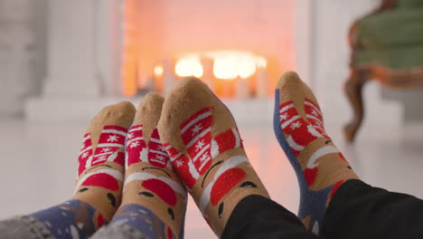 un par de pies en acogedores calcetines navideños cerca de la chimenea