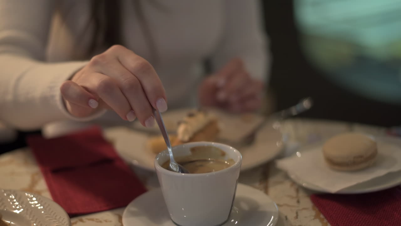 Close up of a woman mixing her coffee at a cafe