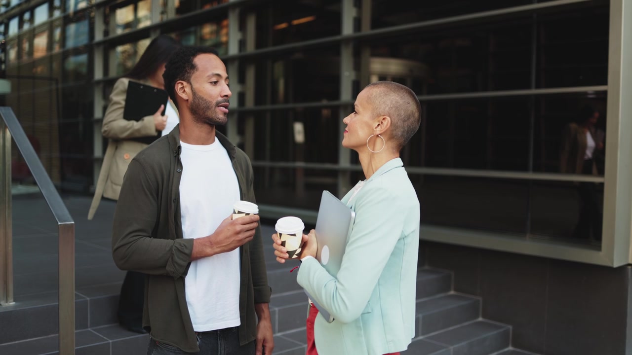 Two Colleagues Talking and Drinking Coffee Outside Modern Office Building