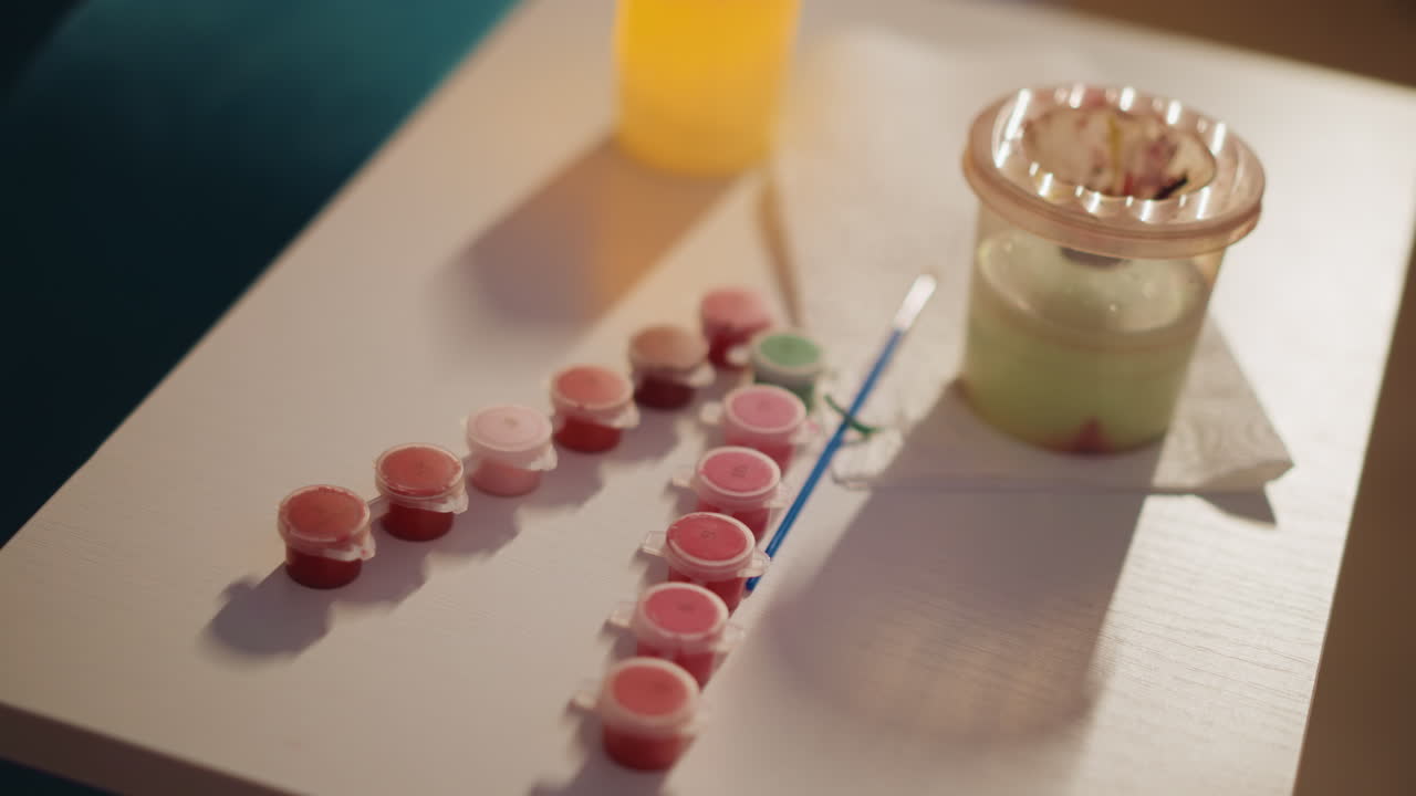 Paint Containers Aligned, Arrangement Of Tiny Paint Pots Next To Brushes And Mixing Vessel, Carefully Ordered Small Paint Containers Positioned Near Brushes And Blending Cup In Cozy Studio Setting