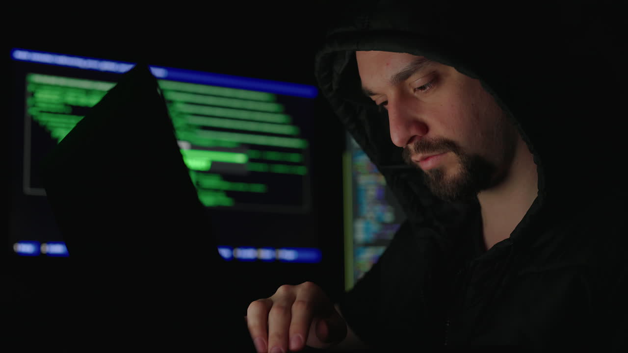 Hacker working on computer code in a dark room