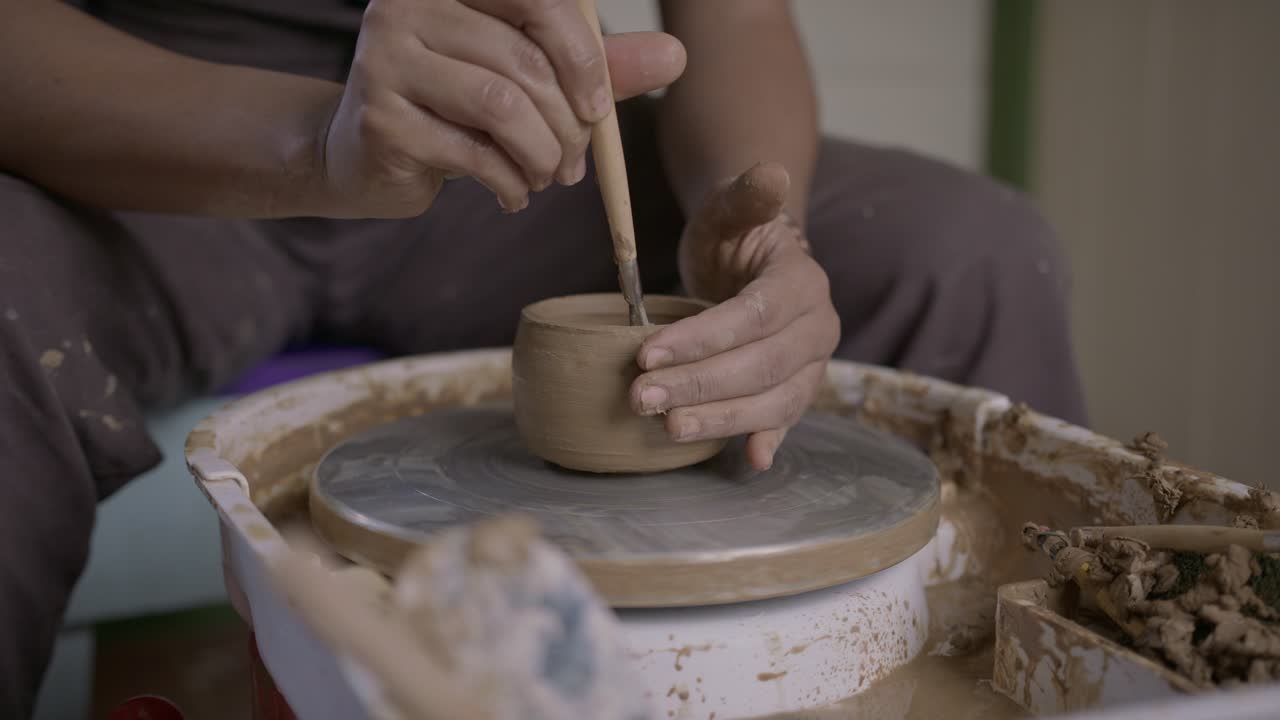 Skilful craftsman concentrates cutting clay pot on turntable with ribbon tool SLOW MOTION
