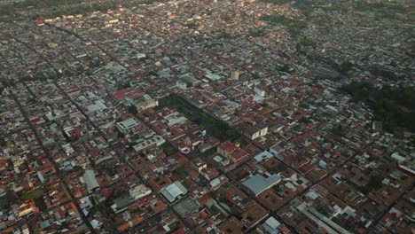 HIGH-ALTITUDE-DRONE-SHOT-OF-URUAPAN-MICHOACAN-MAIN-PLAZA-AT-SUNSET