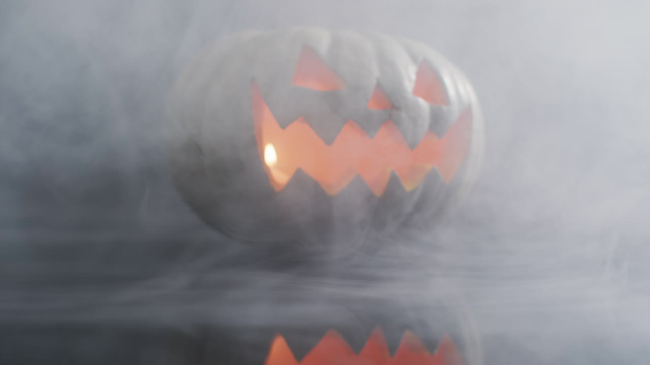 efecto de humo sobre cara aterradora tallada calabaza de halloween contra un fondo gris