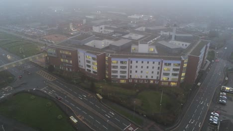 misty foggy hospital building uk town traffic aerial view descent tilt up