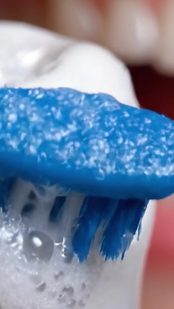 Primo piano dettagliato di uno spazzolino con bolle durante la routine di igiene dentale: importanza di una corretta tecnica di spazzolamento nella cura orale.