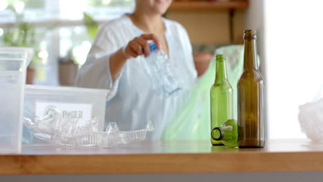 Feliz-Mujer-Birracial-Mayor-Segregando-Botellas-De-Plástico-En-Casa,-Cámara-Lenta