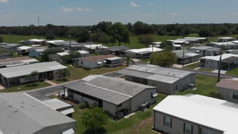 aerial flyover of the sun beat roofs of a trailer park in south florida with adjacent pasture land