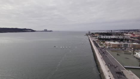 Vuelo-Hacia-Atrás-A-Lo-Largo-Del-Paseo-Marítimo-De-Lisboa-Con-El-Monumento-Padrao-Dos-Descobrimentos