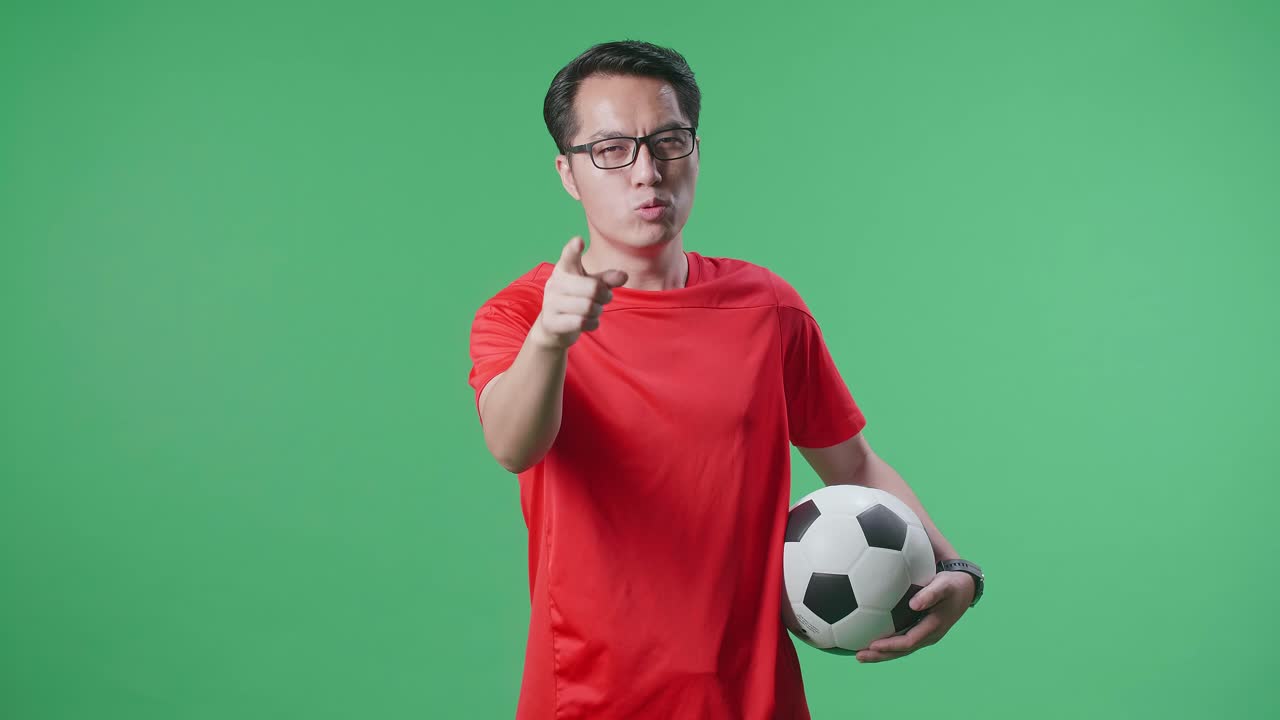 hombre con camiseta roja de fútbol apuntando con una pelota de fútbol