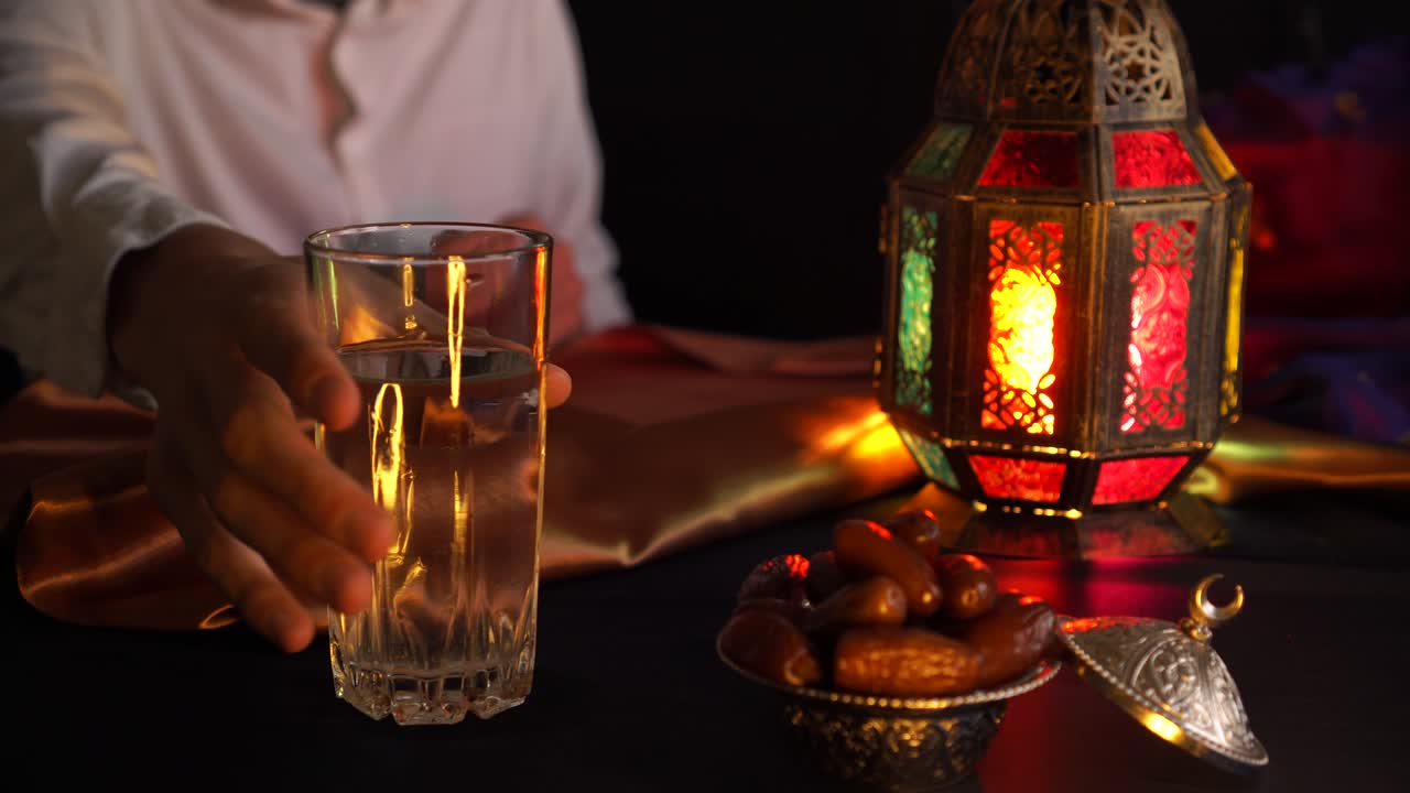 A young man prays and drinks water and eats dates. Evening meal during the Holy Muslim month of Ramadan
