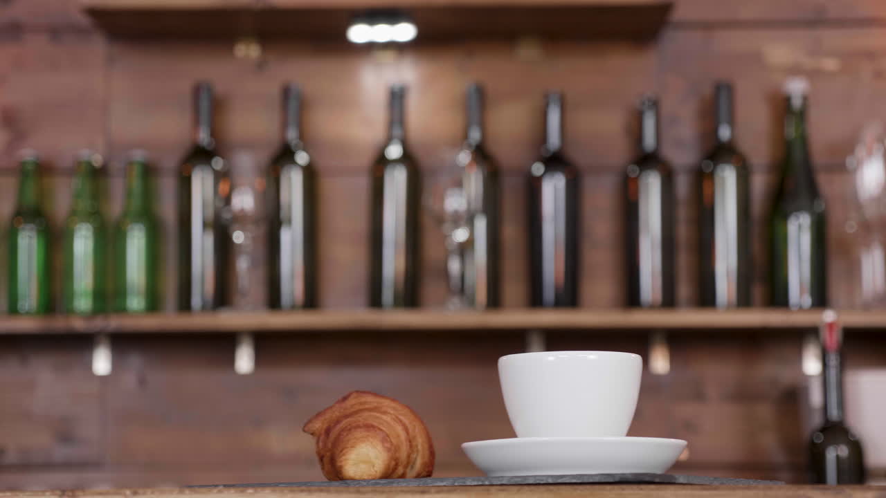 Still life with wine bottles, apples, coffee cup and croissant