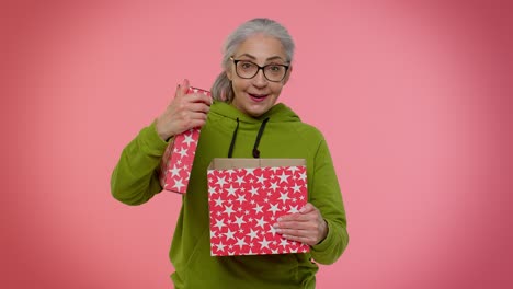 Cheerful-senior-grandmother-woman-opening-gift-box-and-smiling-joyfully,-satisfied-with-nice-present