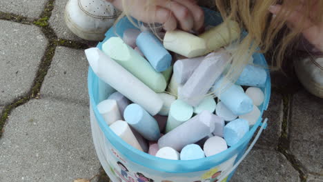 mano del niño buscando el color correcto en un balde de tiza primer plano