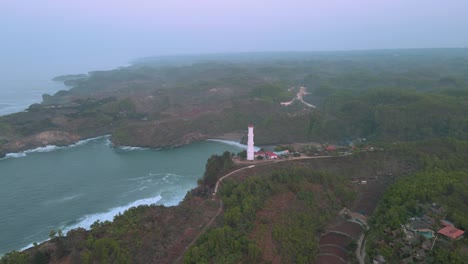 aerial orbiting shot of lighthouse at baron beach during foggy day, indonesia