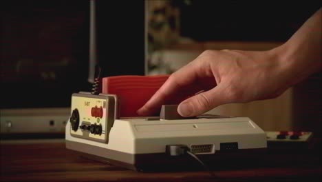 Hand inserting game cartridge into vintage Nintendo Entertainment System (NES)