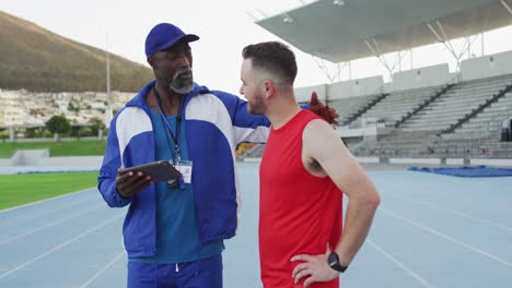 African-american-male-coach-and-caucasian-athlete-talking-during-training-session