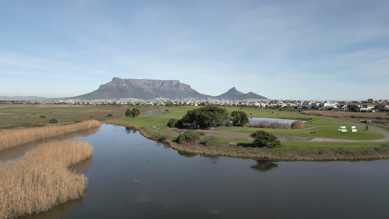Milnerton golf course surrounded by water features with Table Mountain off in the distance