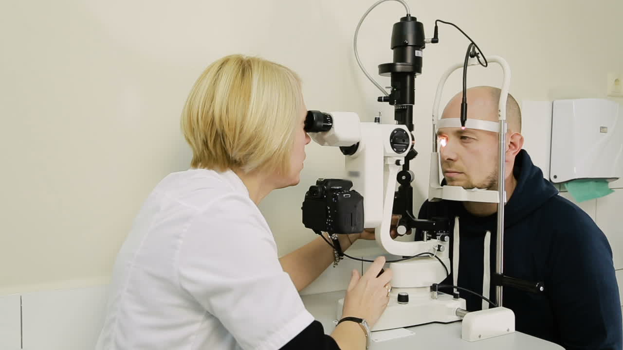 Patient having eye examination. Ophthalmologist measuring intraocular pressure of man in clinic