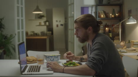 man using laptop while having dinner