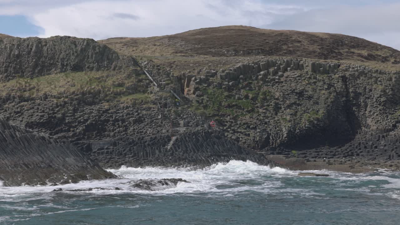 Hand-held shot of waves crashing against basalt rock formations on the isle of Staffa