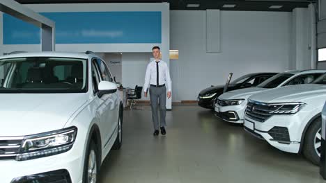 un hombre de negocios caminando por una sala de exhibición de un concesionario de automóviles