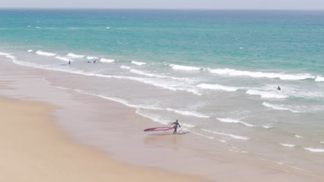 a person taking his windsail and getting ready for windsurfing at the praia do guincho, portugal