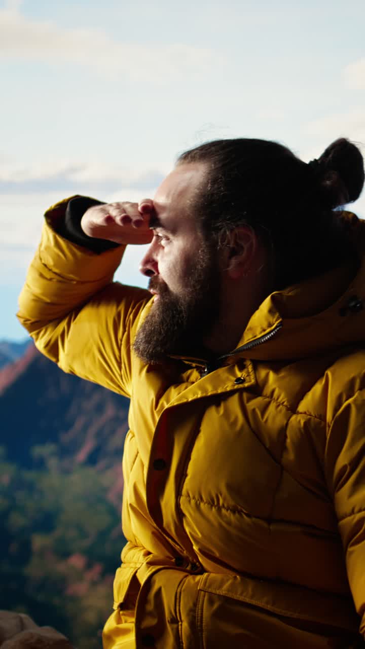 Uomo barbuto che si riposa sulla vetta della montagna dopo un'escursione riuscita