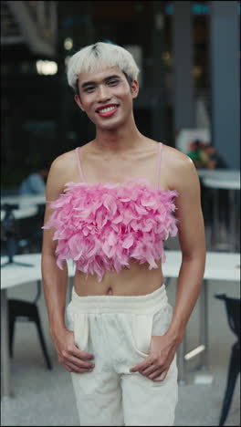 man in pink feather top and white pants