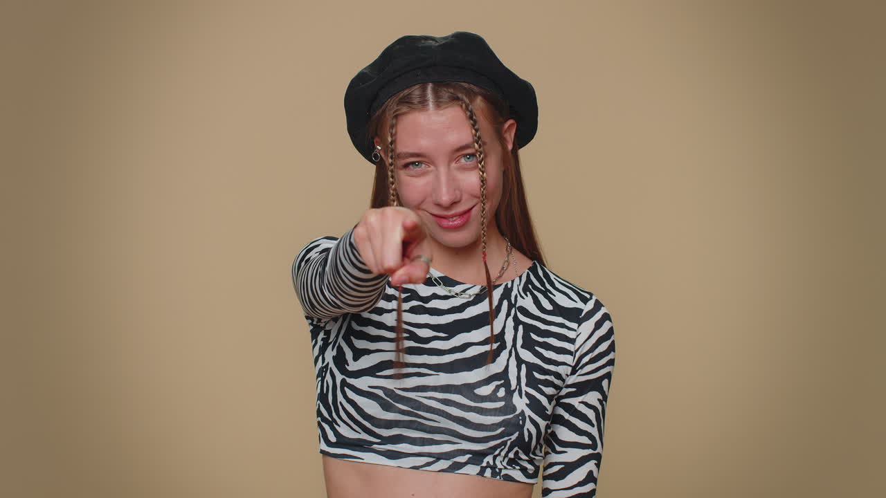 예쁜 젊은 여성이 카메라를 가리키고 장난스러운 행복한 표정으로 선택을 하고 있습니다.