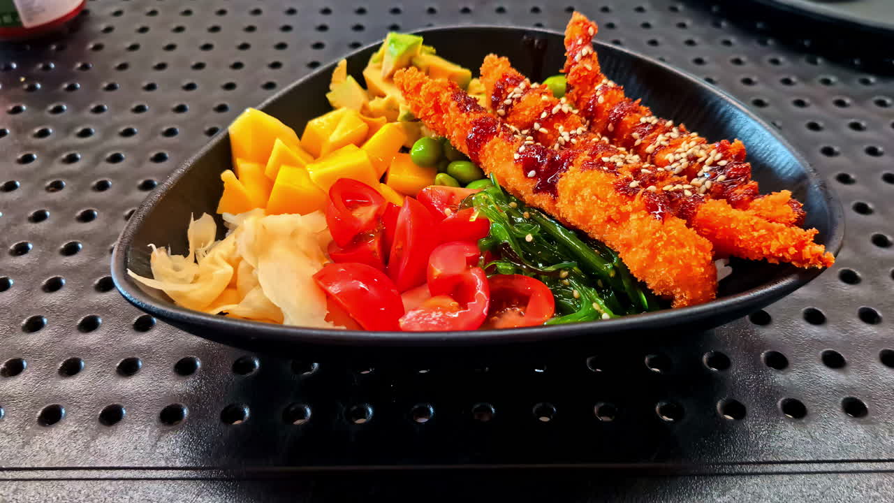 Colorful Asian poke-style bowl with crispy chicken, mango, edamame, and seaweed