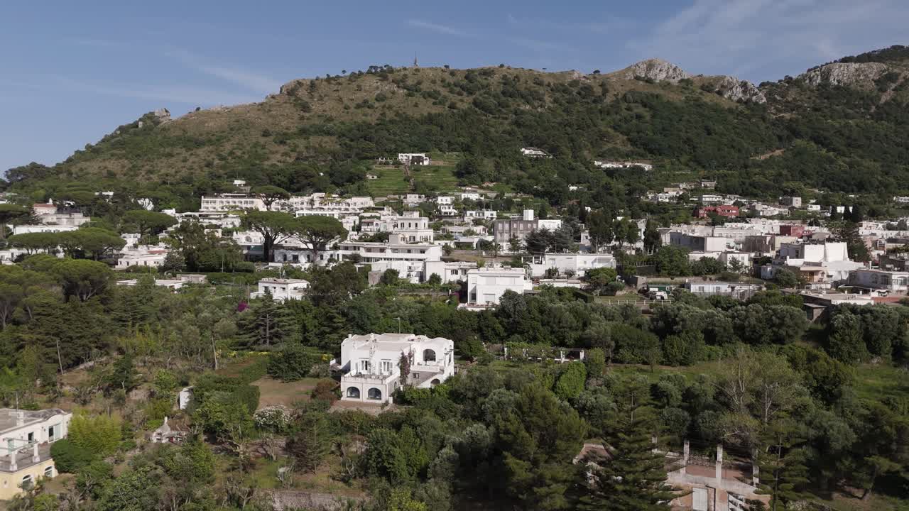Drone shot pushing back, unveiling more white houses and lush nature in Anacapri, Capri Island