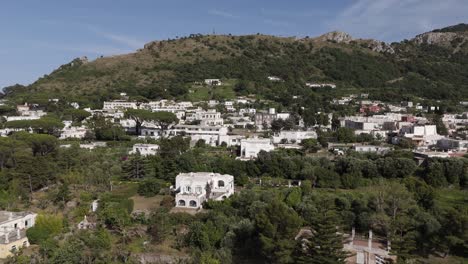 drone shot pushing back, unveiling more white houses and lush nature in anacapri, capri island