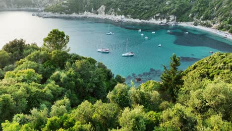 lush greenery framing the tranquil blue waters of liapades beach, corfu during sunset, aerial view