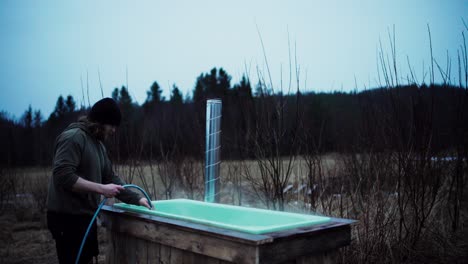 man filling up the hot tub with water from hose