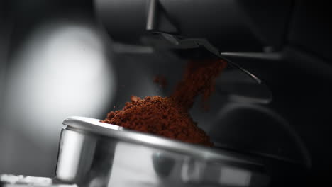 ground coffee pouring out of grinder and falling into portafilter in slow motion and macro