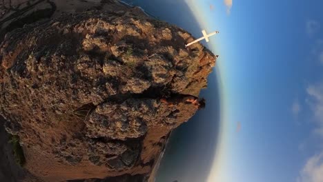 vertical 360 footage of a man hiking to the top next to a cross on porto santo island.