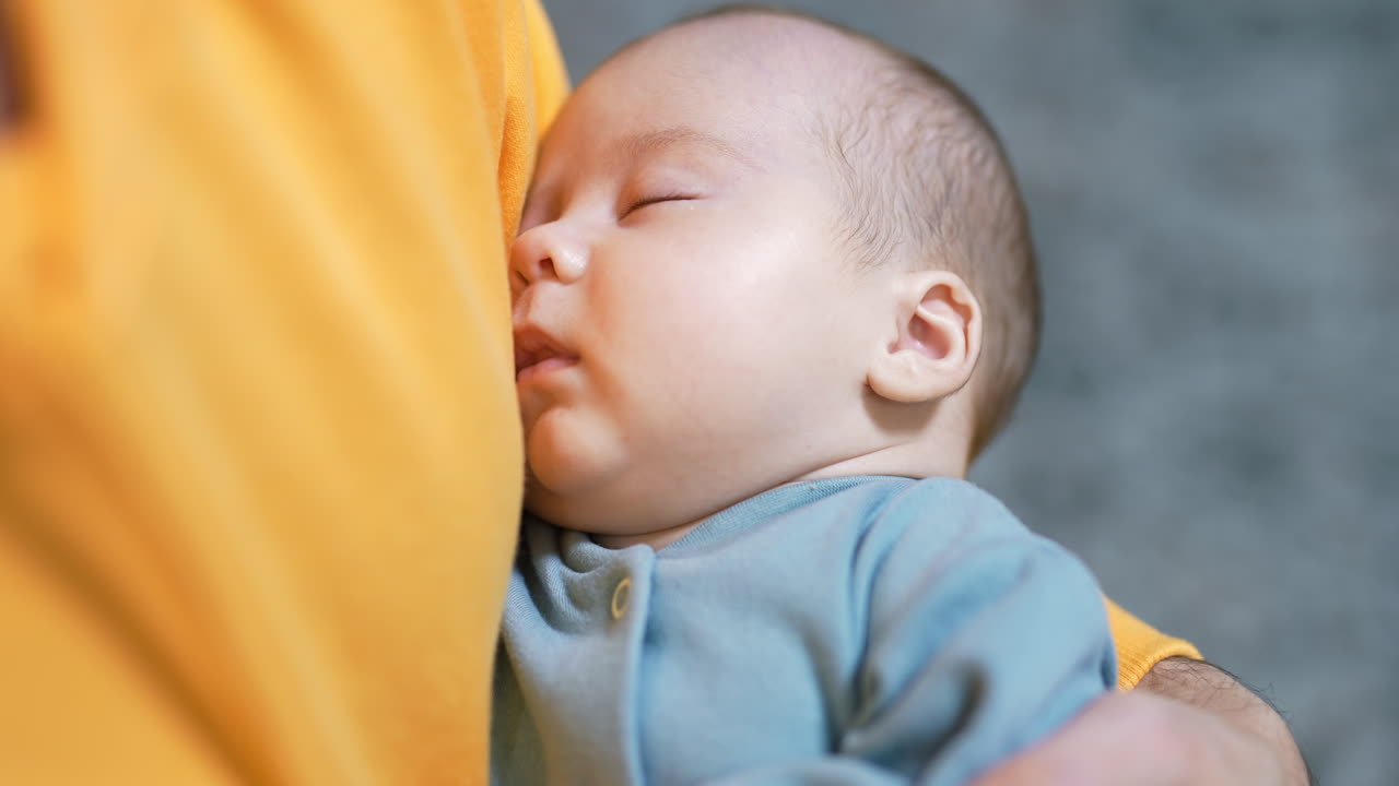 Newborn baby sleeping peacefully in daddy's hands. Adorable sleeping child in a blue suit. Close up.