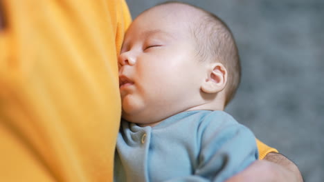 newborn baby sleeping peacefully in daddy's hands. adorable sleeping child in a blue suit. close up.