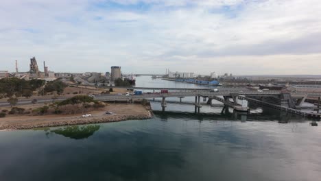 slow flight towards the port adelaide dockyard showing a bridge in the foreground with cars and trucks on it 4k 50p