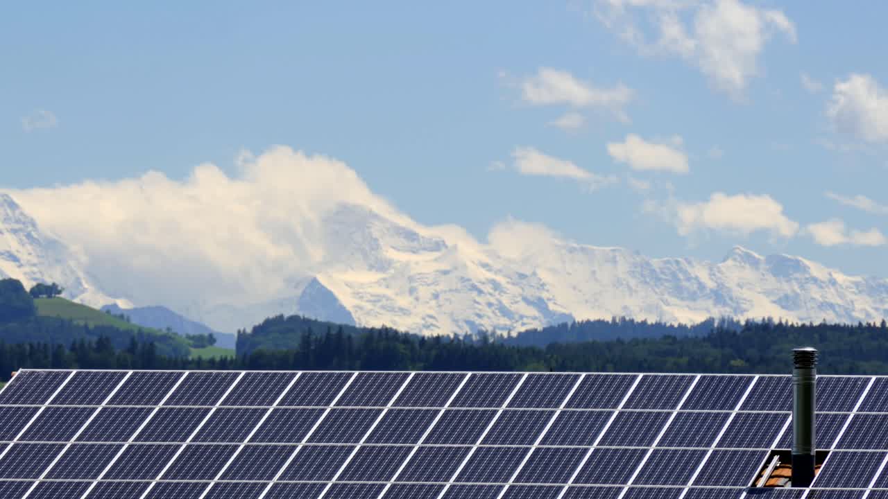 전경에 있는 눈 덮인 알프스와 태양 전지판 사이의 장엄한 구름 움직임