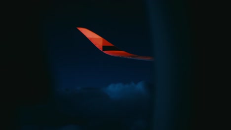 night flight with view from window seat with flickering red positioning light