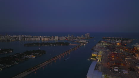 Evening-aerial-footage-of-islands-in-sea-bay.-Busy-multilane-road-leading-at-sea-level-to-luxury-residential-borough.-Miami,-USA