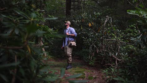 slow motion footage panning in towards a fly fisherman in a temperate forest in the pocono mountains of pennsylvania
