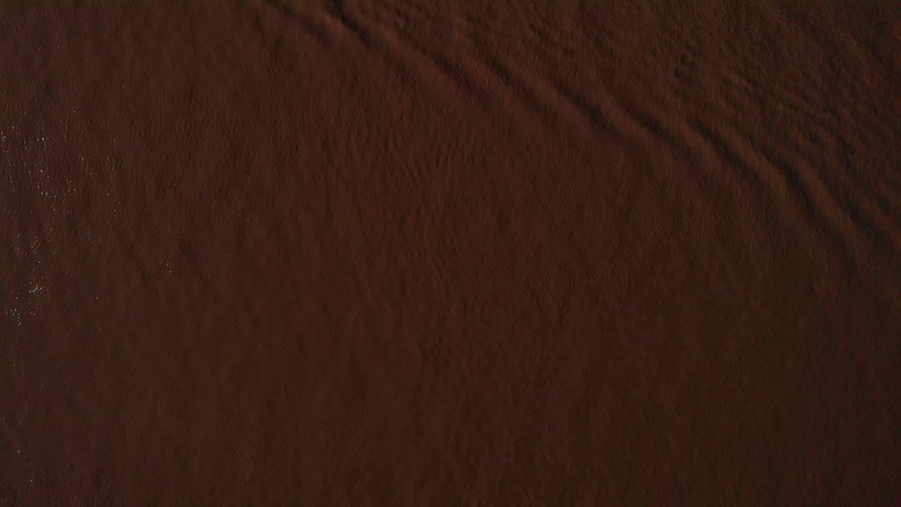 ojo de pájaro aéreo mirando las ondas a través del río de color marrón