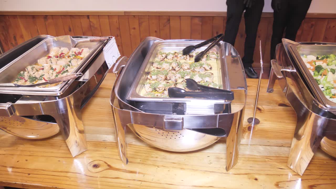 A buffet table is filled with several long, rectangular serving dishes, all containing a variety of savory food