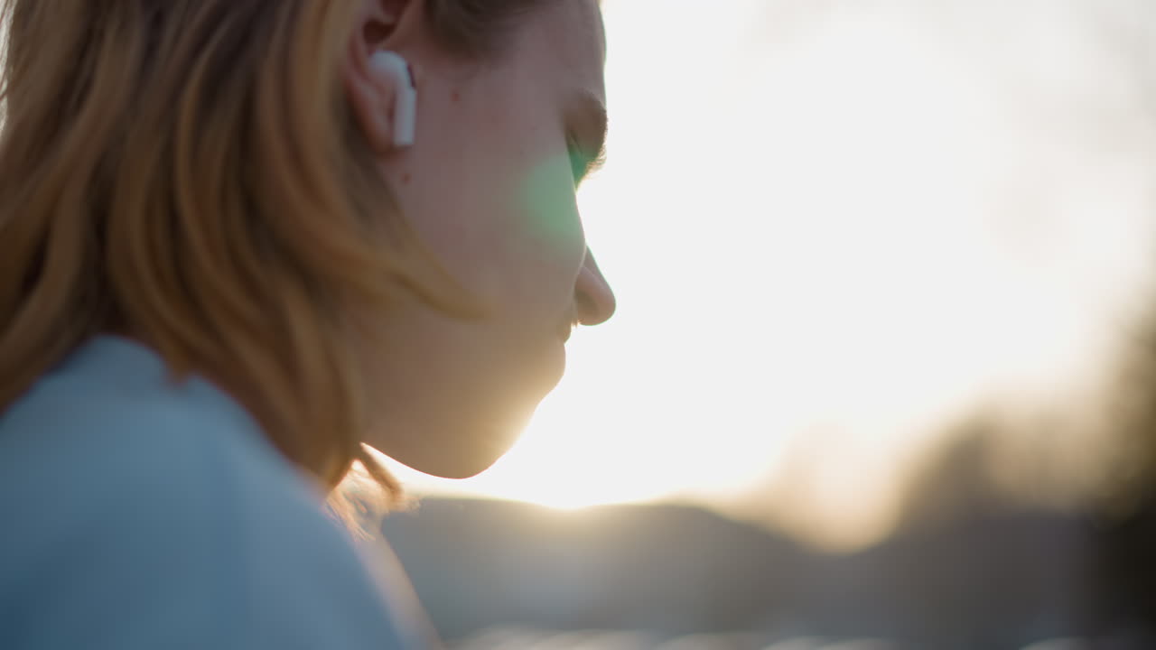 한 여성이 밤의 도시 오디오 환경에 깊이 몰입하며 주의 깊게 듣고 있습니다. 밤에 주변 도시 소음을 주의 깊게 듣는 여성의 친밀한 장면을 클로즈업하여 보여줍니다.
