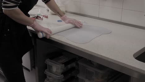 woman rolling out a fresh sheet of icing to decorate handmade butter cookies in a pastry shop, 4k