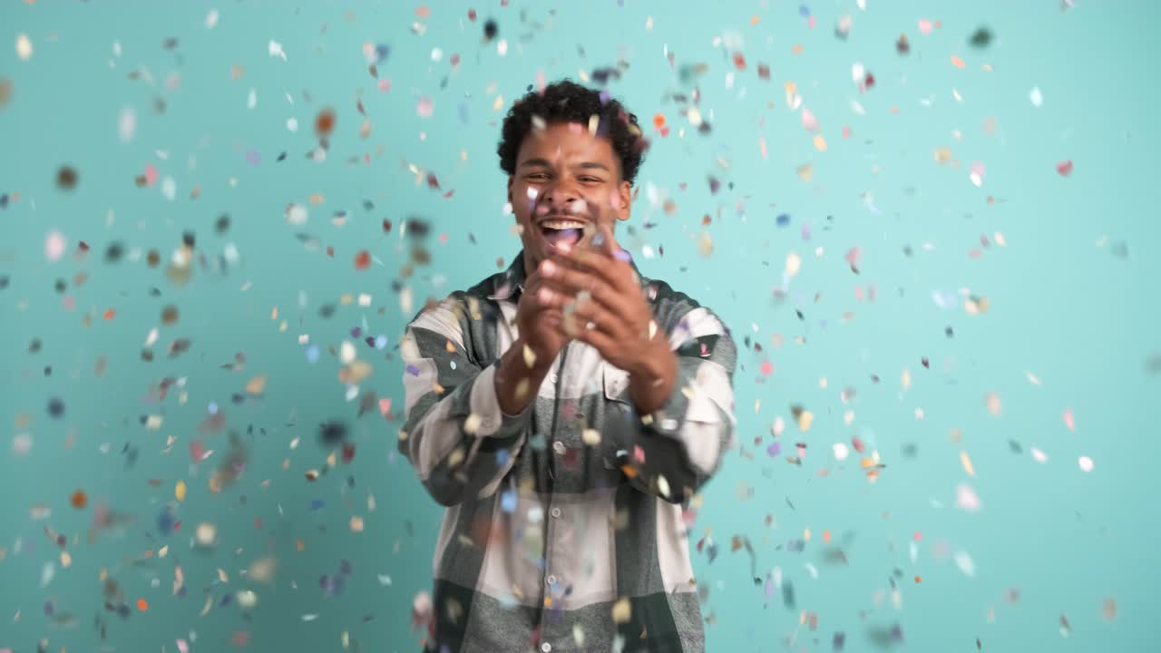 Cheerful man celebrating big win showered in confetti